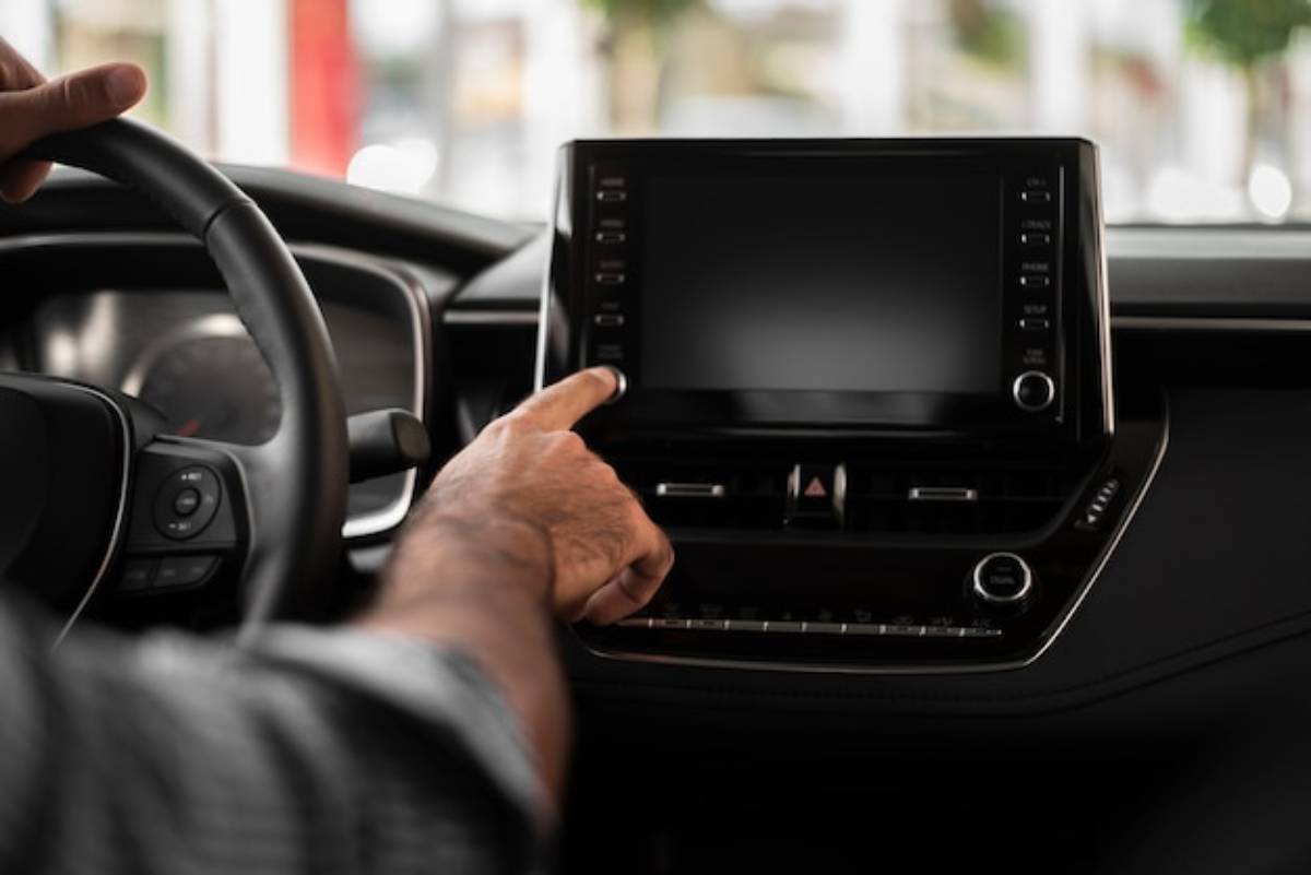 Close-up of a car's steering wheel featuring multimedia control buttons and a red SUPER SPORT ignition button.