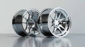 Two gleaming chrome car wheels are displayed on a reflective surface, showcasing intricate designs and polished finishes.