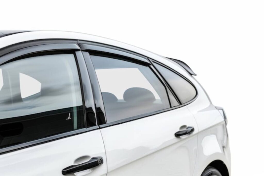 Detail of a white car's side window with black trim and handles, showcasing a sleek design against a white background.