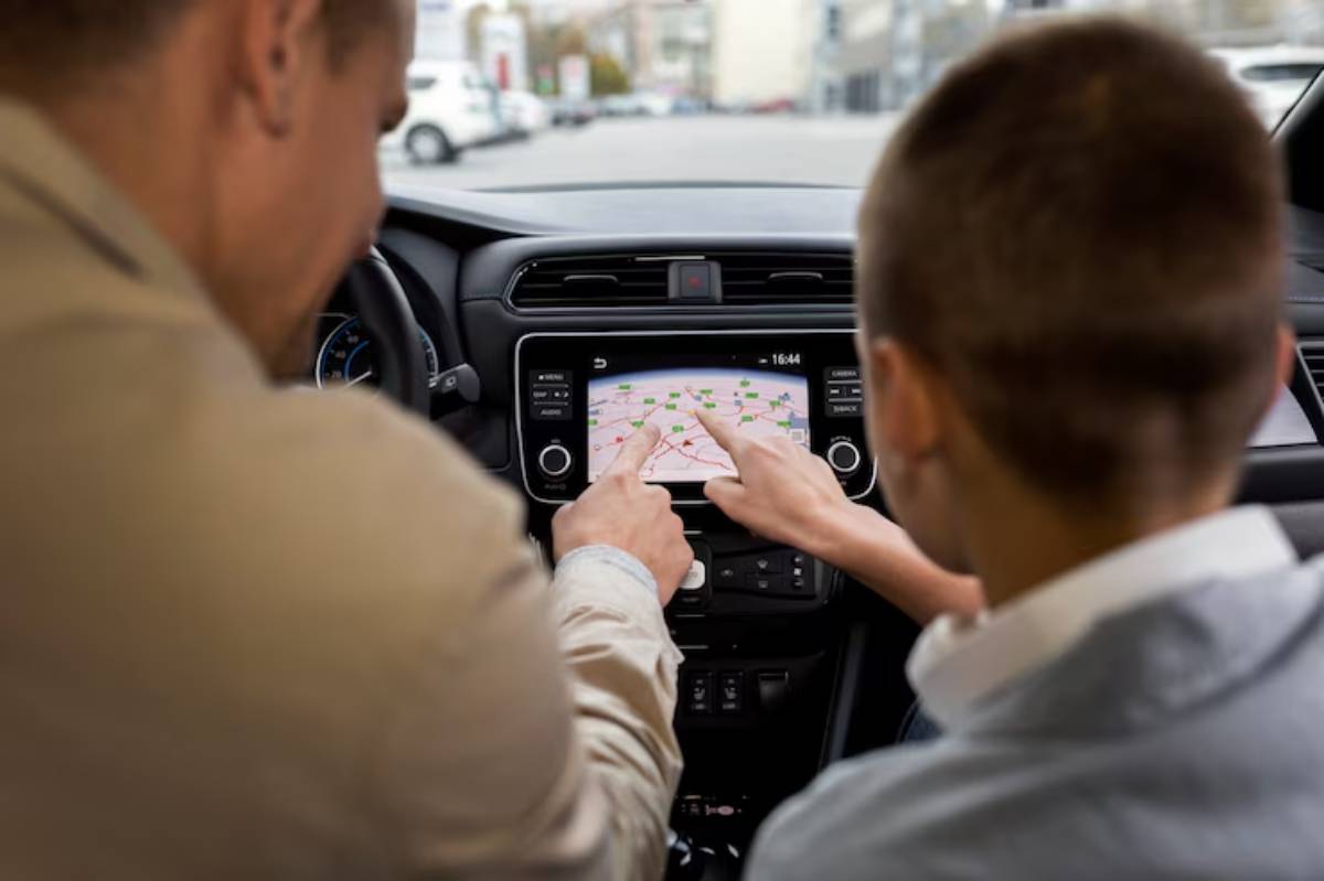 Two individuals are using a car's touchscreen GPS, pointing at the map displayed, with a focus on navigating their route.