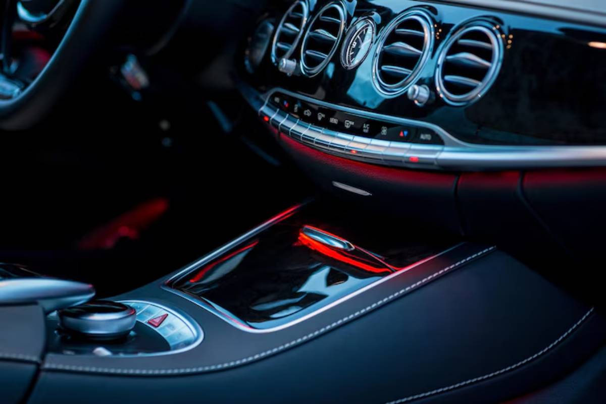 Close-up of a luxury car's interior, featuring sleek black leather, illuminated controls, and modern design elements.