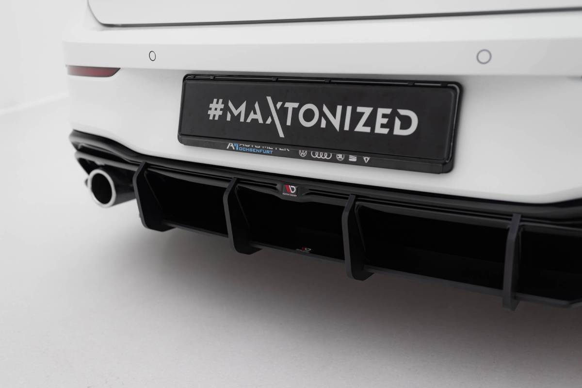 Close-up of a white car's rear featuring a black bumper diffuser and a license plate with the hashtag MAXTONIZED.
