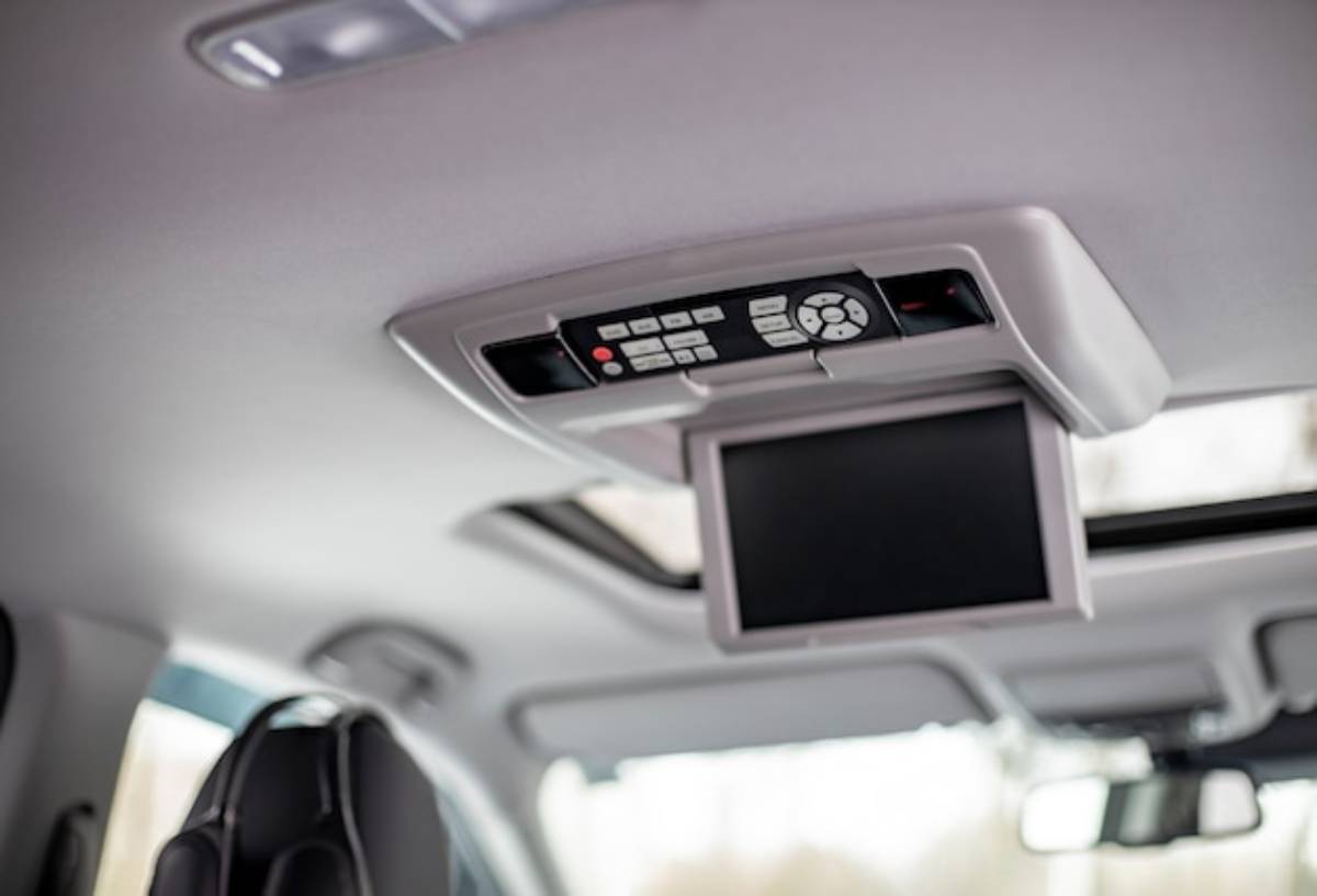Close-up of a car's ceiling-mounted entertainment system featuring a small screen and remote control buttons.