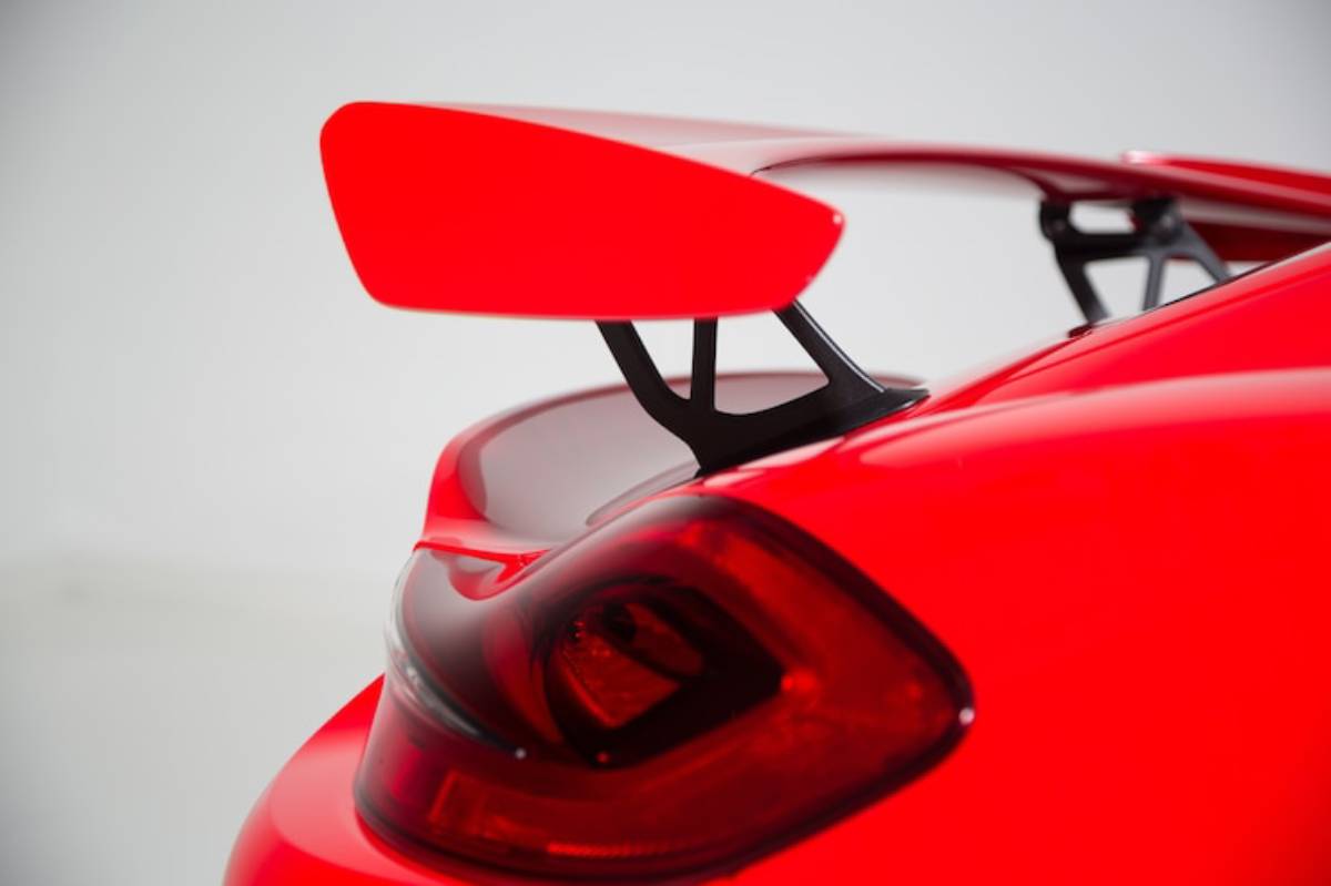 Close-up of a red sports car's rear, showcasing a prominent large wing and sleek tail light design.