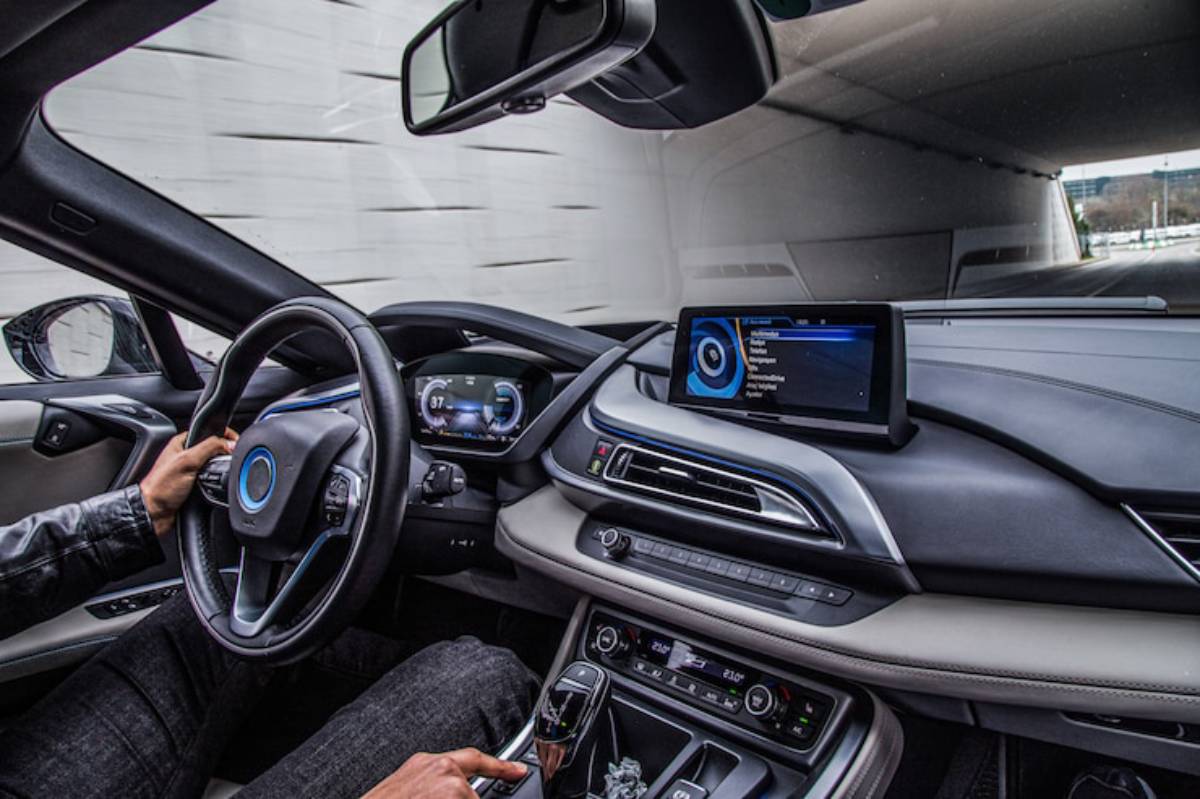 Interior view of a sleek car with a driver’s hand on the steering wheel, featuring a high-tech dashboard and navigation display.