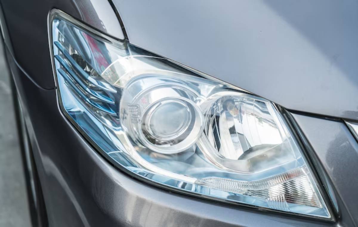 Close-up view of a modern car's sleek headlight, showcasing its clear glass design and reflective elements.